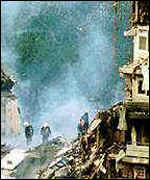 [ image: Rescuers sift through the rubble of the apartment block]